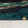 A close-up view of a rug with a marble-like pattern, showing the texture and edge detail. A coin is placed on the edge for scale. Náhled obrázku produktu