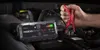 A person is using a jump starter to boost a car battery in an engine bay. Podgląd zdjęcia produktu