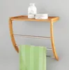 A wooden shelf with metal towel bars mounted on a gray wall, holding a green striped towel and two bathroom products. Náhled obrázku produktu