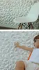 A child is touching a textured white wall panel, with a chair in the background. Produktbild-Vorschau