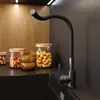 A modern kitchen sink area with a black faucet, wooden cabinets, and glass jars filled with nuts. Podgląd zdjęcia produktu