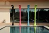 Four colorful outdoor showers stand by a swimming pool. Produktbild-Vorschau