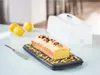 A lemon cake on a serving tray with lemons and a cake carrier in the background. Náhľad obrázku produktu