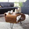 A wooden coffee table with a curved design, placed in a living room setting with a blue sofa and decorative vases. Produktbild-Vorschau