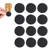 A hand is holding a wooden furniture leg with an anti-slip pad attached to the bottom. Several other anti-slip pads are arranged in a grid pattern to the right. Produktbild-Vorschau