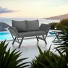 A grey rattan sofa with cushions sits on a patio next to a pool with a view of the ocean and islands. Voir les images du produit