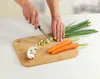 A person is chopping vegetables on a bamboo cutting board. Produktbild-Vorschau
