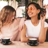 Two young women sitting at a table with coffee cups. Produktbild-Vorschau