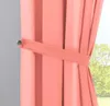 A close-up of a coral-colored curtain held back by a tie-back, with a window and trees visible in the background. Produktbild-Vorschau