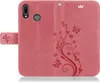 A pink flip cover phone case with a floral and butterfly design. Produktbild-Vorschau