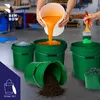 A person is pouring orange liquid from a white bucket into a green bucket, while another green bucket is filled with foam, and a third green bucket is tipped over spilling dirt. A paintbrush with green paint is also visible. Anteprima dell’immagine prodotto