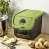 A kitchen counter with a storage box for potatoes and onions, along with some onions and a knife. Produktbild-Vorschau