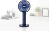A dark blue portable fan is displayed on a white surface, with a blurred background of office items. Anteprima dell’immagine prodotto