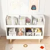 A white bookshelf filled with books and decorative items, set against a white paneled wall. Náhľad obrázku produktu