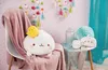 A plush toy rabbit with a chick peeking out of its head, sitting on a chair draped with a pink blanket. The background features a pink polka-dot wallpaper with colorful tassel decorations and a teal curtain. Produktbild-Vorschau