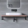 A modern bathroom sink console with a white basin, a wooden shelf, and black fixtures mounted on a gray tiled wall. Produktbild-Vorschau