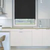 A modern kitchen with white cabinets and a window covered by a black roller blind. Produktbild-Vorschau