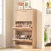 A wooden shoe cabinet with multiple shelves filled with shoes, placed in a room near a doorway and a sofa. Voir les images du produit