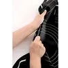 Hands holding a black silicone baking mat with white markings. Voir les images du produit
