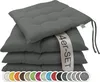 A stack of four dark gray seat cushions with a promotional band across them. Voir les images du produit
