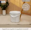 A white diaper pail sits on a light-colored rug in front of a wooden wall. A vase with greenery is to the left. Produktbild-Vorschau