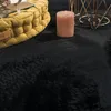A close-up view of a black shag rug with a yellow floor cushion and a pink candle. Voir les images du produit
