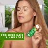 A woman is holding a bottle of hair oil, with a green overlay text on the left side of the image. Produktbild-Vorschau