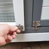 A hand is shown closing a latch on a wooden pet house. Produktbild-Vorschau