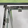 Close-up of a shower door mechanism, showing rollers and glass edges. Produktbild-Vorschau