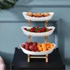 A three-tiered serving stand filled with fruit and pastries, set against a blue wall. Náhled obrázku produktu