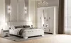 A well-lit bedroom scene featuring a white wardrobe and bed. Produktbild-Vorschau