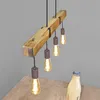 A wooden beam pendant light with multiple Edison bulbs hangs over a wooden table, with a milk bottle and glasses visible. Anteprima dell’immagine prodotto