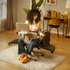 A woman is working on her laptop while sitting in a unique office chair, with a small dog beside her. Podgląd zdjęcia produktu