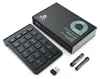 A black wireless numeric keypad, its packaging, two batteries, and a USB receiver are arranged on a white background. Náhled obrázku produktu