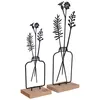 Two decorative metal flower arrangements in bottle-shaped vases, each on a wooden base. Produktbild-Vorschau