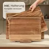 A hand is shown placing a wooden cutting board on top of another cutting board, which is part of a set displayed on a stand. Produktbild-Vorschau