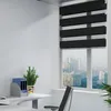 An office desk with a computer mouse, keyboard, a plant in a pot, and a blue folder holder with folders, next to a window with blinds and a city view. Voir les images du produit