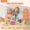 A mother and daughter are using a mini pottery wheel, with various pottery tools and finished pieces displayed on a table. Produktbild-Vorschau