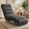 A gray chaise lounge chair is shown in a living room setting with a lamp, a plant, and a side table. Produktbild-Vorschau