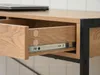 Close-up of an open desk drawer, showing the wooden interior and metal drawer slides. A laptop is visible on the desk surface above. Podgląd zdjęcia produktu