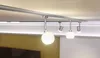 A track lighting system with multiple globe-shaped lights mounted on a silver track attached to a ceiling. Náhľad obrázku produktu