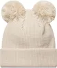 A close-up studio shot of a beige knitted winter hat with two pom-poms on top. Produktbild-Vorschau
