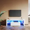 A modern white TV stand with RGB lighting, displaying a television and some decorative items. Náhled obrázku produktu