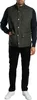 A man wearing a green quilted vest over a navy blue sweater and black pants. Produktbild-Vorschau