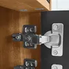 Close-up view of cabinet hinges attached to wooden and black surfaces. Produktbild-Vorschau