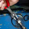 A close-up shot of a person using KNIPEX TwinGrip pliers to grip a metal fitting on a blue industrial machine. Voir les images du produit
