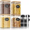 Four clear glass storage jars with bamboo lids, filled with coffee beans, pasta, fusilli, and nuts. Each jar has a black oval label with white text indicating its contents. Náhled obrázku produktu