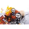 Three Halloween-themed plush toys are arranged with pumpkins, autumn leaves, and faux spiderwebs. Produktbild-Vorschau