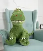 A green plush dinosaur toy sits on a light blue armchair. Anteprima dell’immagine prodotto