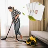 A woman is vacuuming a wooden floor in a room with curtains and a sofa. There are also images of vacuum cleaner bags floating in the air. Voir les images du produit